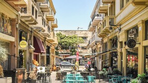 A narrow street with outdoor seating and shops on either side.