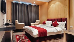 A modern hotel room with a large bed, two armchairs, a wooden headboard, and a flat-screen TV mounted on the wall. - Hotel Highland Bhagsu (Dharamshala)