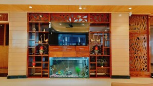 Un hall de hotel con un mostrador de recepción de madera, un gran acuario y elementos decorativos.