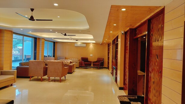 Un moderno vestíbulo de hotel con un área de estar central, paneles de madera y un letrero que dice 'WELCOME'.