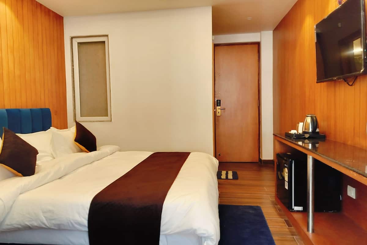 A hotel room with a bed, a TV mounted on the wall, and a coffee machine.