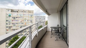 A balcony with a table and chairs, overlooking a residential building with multiple balconies.