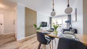 A modern dining area with a wooden table, black chairs, and a vase of flowers.