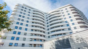 Un immeuble moderne à plusieurs étages, doté d’une façade incurvée, de nombreux balcons et d’une grande fenêtre au rez-de-chaussée.