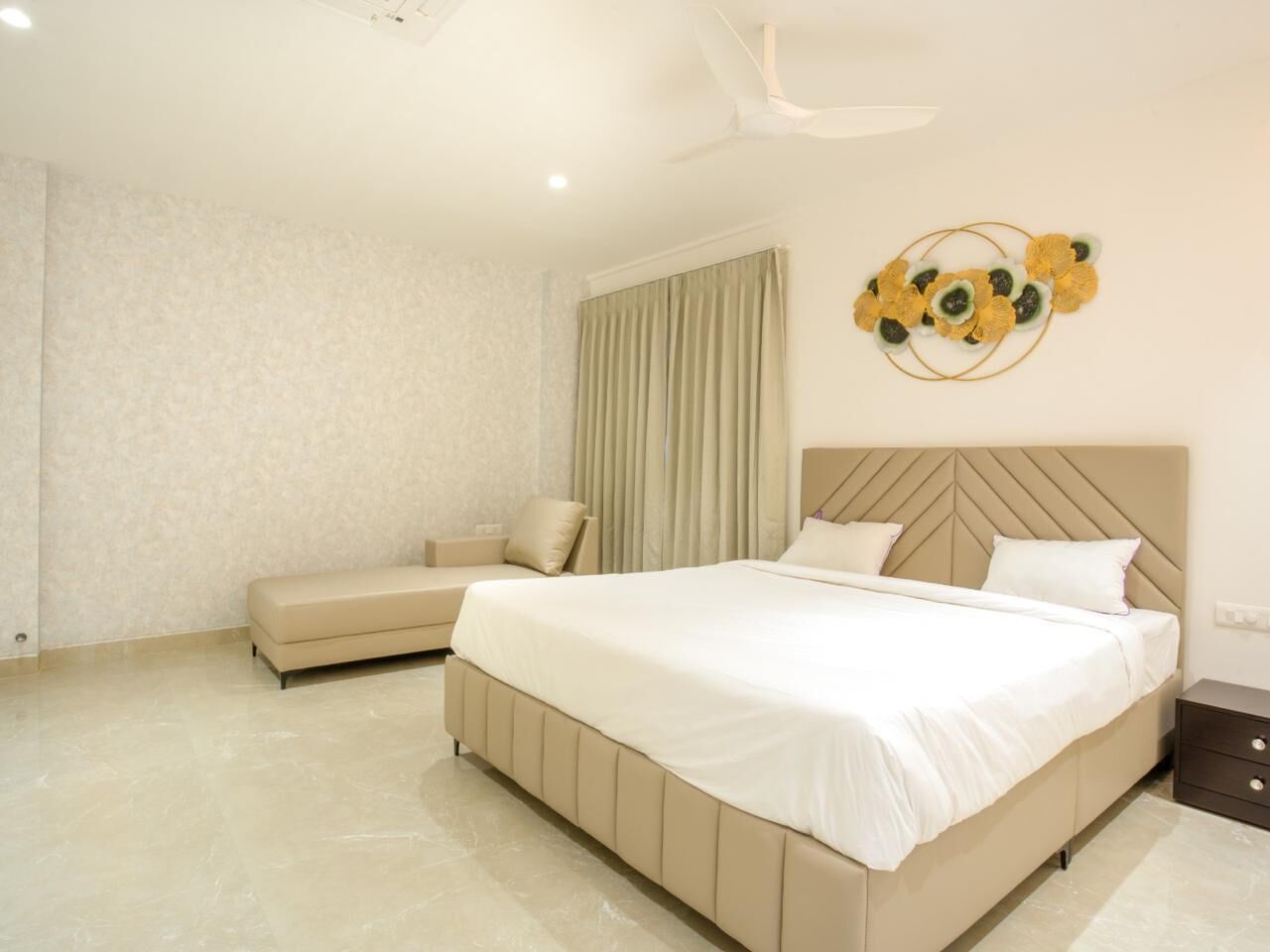 A bedroom with a large bed, a bench, and a decorative wall piece.