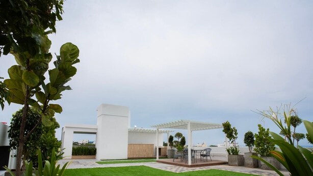 A modern outdoor patio area with a white pergola, a grassy lawn, and a seating area with a table and chairs. - Let Home (Hyderabad)