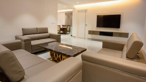 A modern living room with a sofa set, a coffee table, and a flat-screen TV mounted on the wall. - Let Home (Hyderabad)