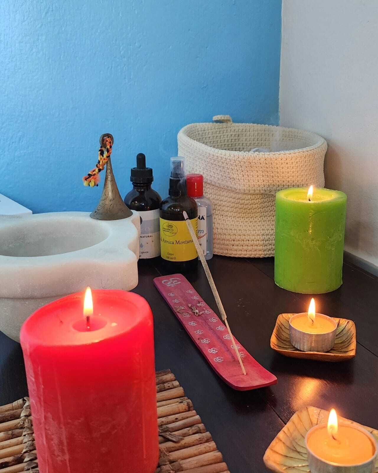 A room with a blue wall, a white basin, and several candles of different sizes and colors.