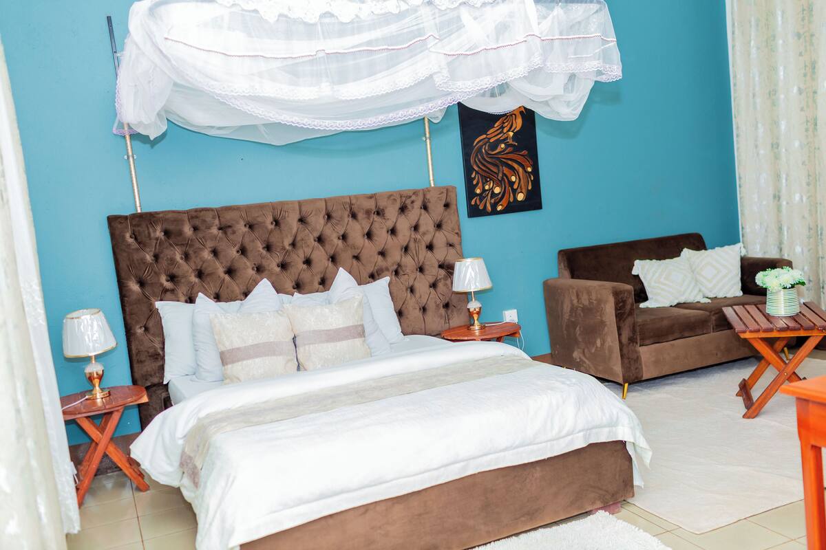 Une chambre avec un grand lit, un canapé marron, une petite table et une décoration murale.