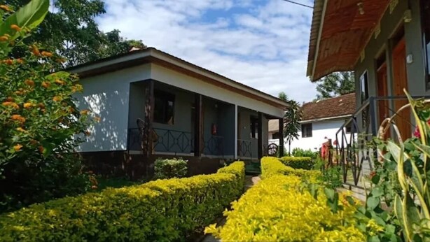 Une maison à deux étages avec un porche abrité et un jardin bien entretenu.