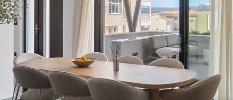 Un comedor moderno con una mesa de madera y seis sillas, un cuenco de limones y una lámpara colgante.