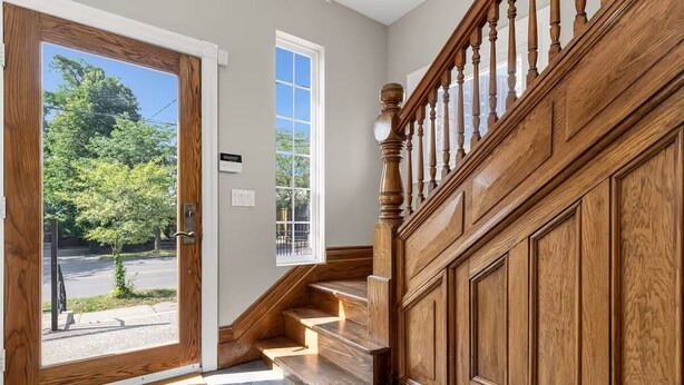 Una escalera de madera con barandilla que lleva a un piso superior.