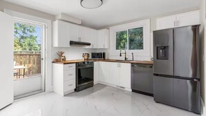 Una cocina moderna con armarios blancos, un refrigerador de acero inoxidable y un horno empotrado.