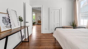 Un dormitorio con cama, mesita de noche, cómoda y ventana con cortinas.