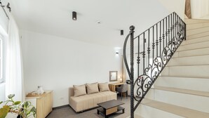 Un salon comprenant un canapé, une table basse, un bureau et un escalier orné de balustrades décoratives.