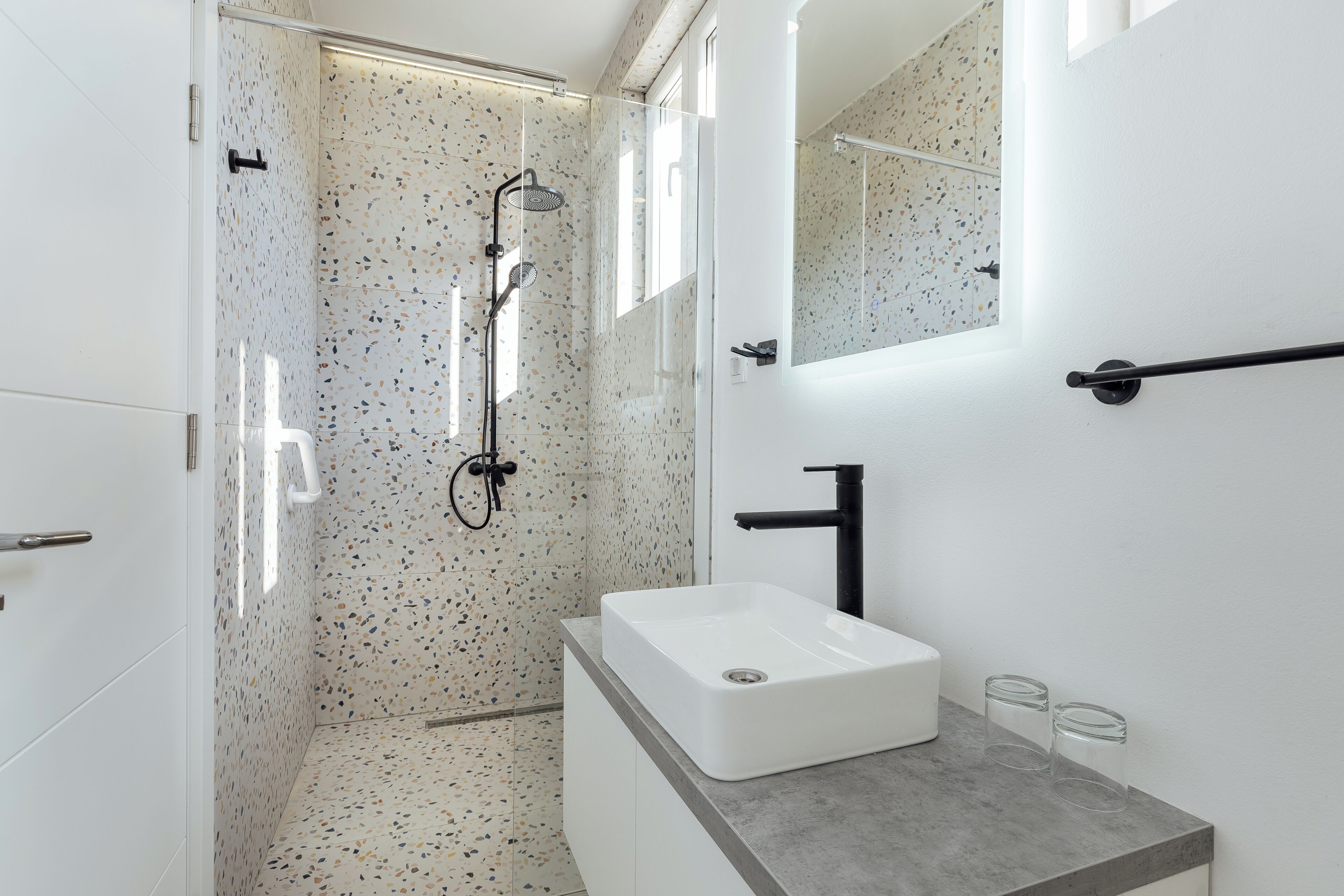 A modern bathroom with a shower, a sink, and a mirror.