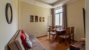 A living room with a sofa, a dining table with chairs, and a TV. - 8 Minutes From Copacabana Beach Br1010 (Rio de Janeiro)