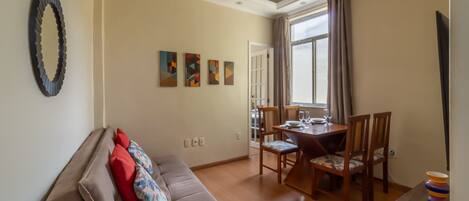 Una sala de estar con sofá, una mesa de comedor con sillas y televisor.