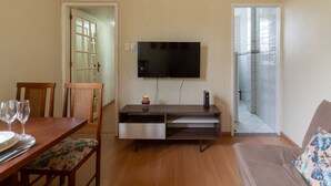 A living room with a TV mounted on the wall, a dining table with chairs, and a sofa. - 8 Minutes From Copacabana Beach Br1010 (Rio de Janeiro)