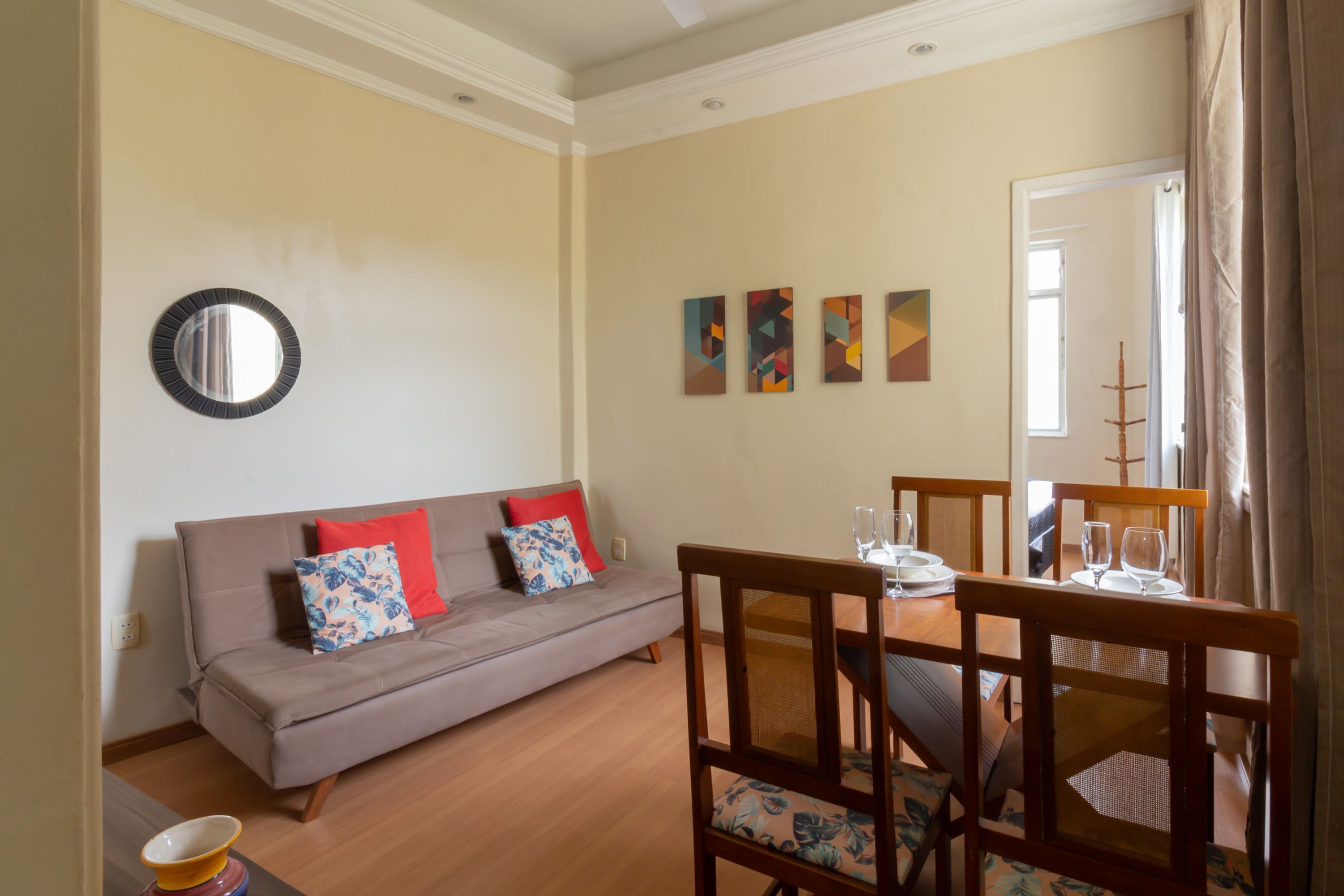 A living room with a sofa, chairs, a dining table, and artwork on the wall.