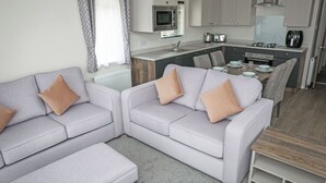 Una sala de estar moderna con un sofá gris, una mesa de comedor y una cocina con electrodomésticos.