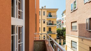 Un estrecho callejón entre edificios con balcones, una barandilla metálica y una pequeña escalera que baja.