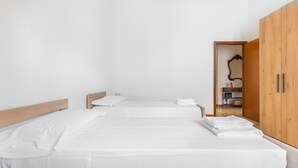 Un dormitorio minimalista con dos camas, cabeceros de madera y un armario de madera.