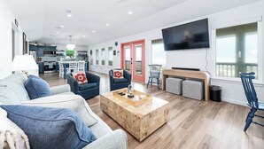 Een moderne woonkamer met een houten salontafel, blauwe banken en een grote televisie.