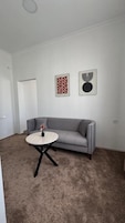 Una sala de estar con un sofá gris, una mesa de centro redonda y dos obras de arte enmarcadas en la pared.