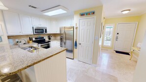 A modern kitchen with white cabinets, stainless steel appliances, and a granite countertop.