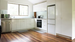 A modern kitchen with white cabinets, stainless steel appliances, and a wooden floor.