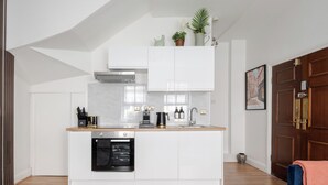 Una cucina moderna con mobili bianchi, forno integrato e macchina per il caffè.