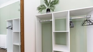 A room with a white wardrobe, a coat rack, and a potted plant.