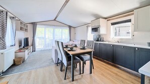 A compact kitchen with dark cabinets, a microwave, and a window. - Wave Whisperers - Hayling Island (Hayling Island)