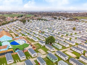 Um amplo parque de caravanas com fileiras de trailers, uma piscina e quadra de tênis.