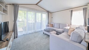 A modern living room with a sofa set, a flat-screen TV, and a large window with curtains. - Wave Whisperers - Hayling Island (Hayling Island)