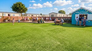 A sunny outdoor area with picnic tables and a food stand named 'Eats N' Treats'. - Golden Dune - Hayling Island (Hayling Island)