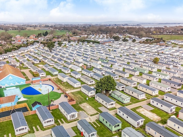 A large caravan park with rows of caravans, a swimming pool, and a tennis court.