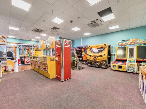 An indoor arcade with various gaming machines, including a Transformers-themed game and a claw machine.