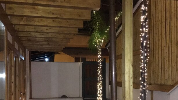 Un espacio al aire libre cubierto con techo de madera, alfombra roja y luces colgantes.