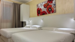 Una habitación de hotel con dos camas, un cuadro grande con motivos florales en la pared y un armario.