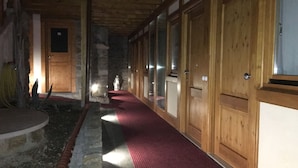 Un pasillo con puertas de madera, alfombra roja y paredes de piedra.