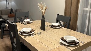 A dining area with a wooden table set for four, surrounded by dark chairs. A vase with dried flowers is placed in the center. - 3-bedroom house in peaceful Independence. Enjoy your stay (Independence)