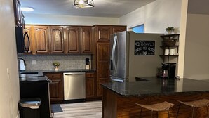 A modern kitchen with wooden cabinets, a stainless steel refrigerator, a coffee machine, and a sign indicating a coffee, tea, and bar area. - 3-bedroom house in peaceful Independence. Enjoy your stay (Independence)