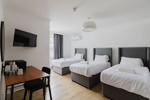 Une chambre d’hôtel avec deux lits, une télévision, une table à manger et une fenêtre avec des rideaux.
