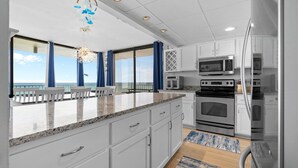 Une cuisine moderne avec des armoires blanches, des appareils en acier inoxydable et un grand îlot central.