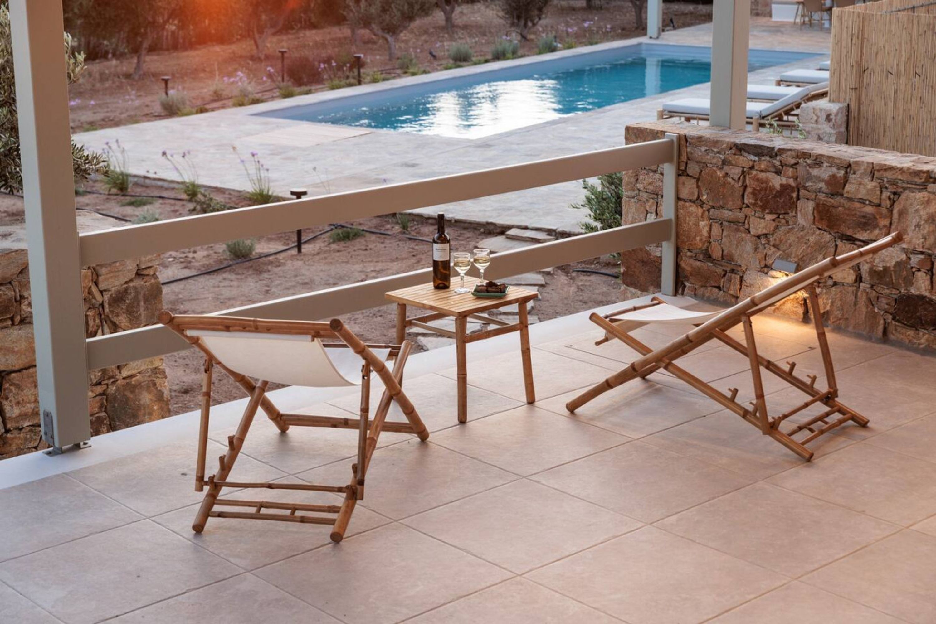 A patio area with a table and chairs, a bottle of wine, and a glass.