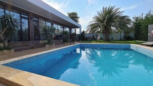 A modern house with a swimming pool, large windows, and tropical plants. - Dachis Villa (Batumi)