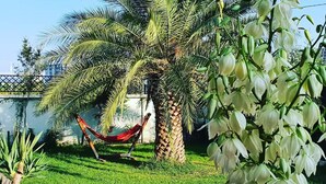 A hammock under a palm tree in a well-maintained garden with a pathway. - Dachis Villa (Batumi)