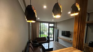 A modern living room with a wooden dining table, a sofa, and a TV mounted on the wall. - Dachis Villa (Batumi)
